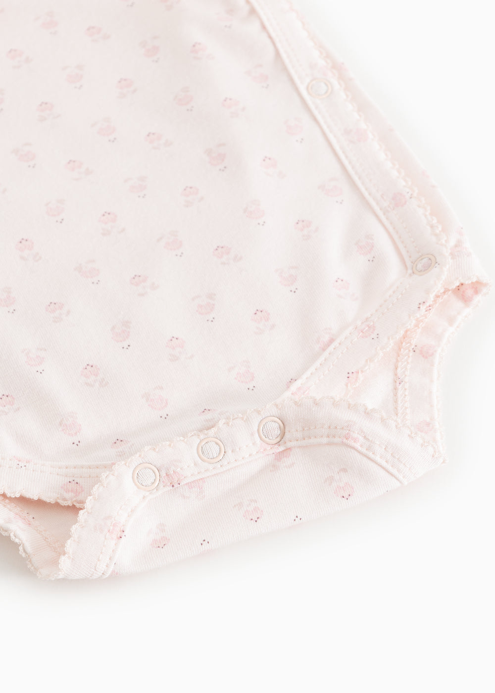 Lys rosa bodystocking med blomsterprint, knaplukning i skridt og flæsekant ved ben