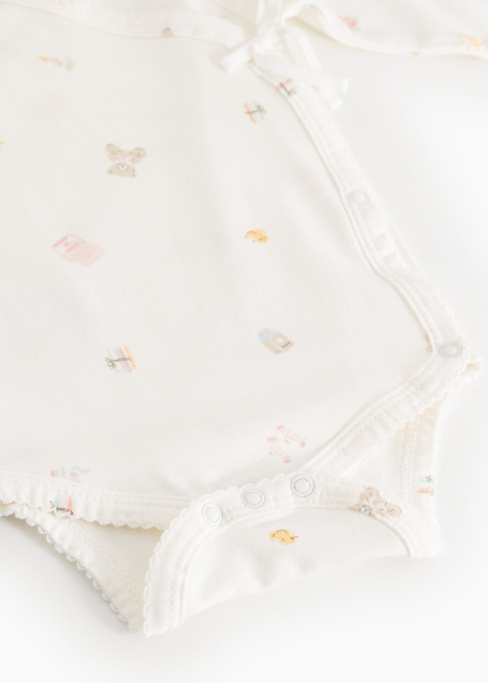 Bodystocking offwhite med smalt mønster, rynket kant og trykknapper i skridt.