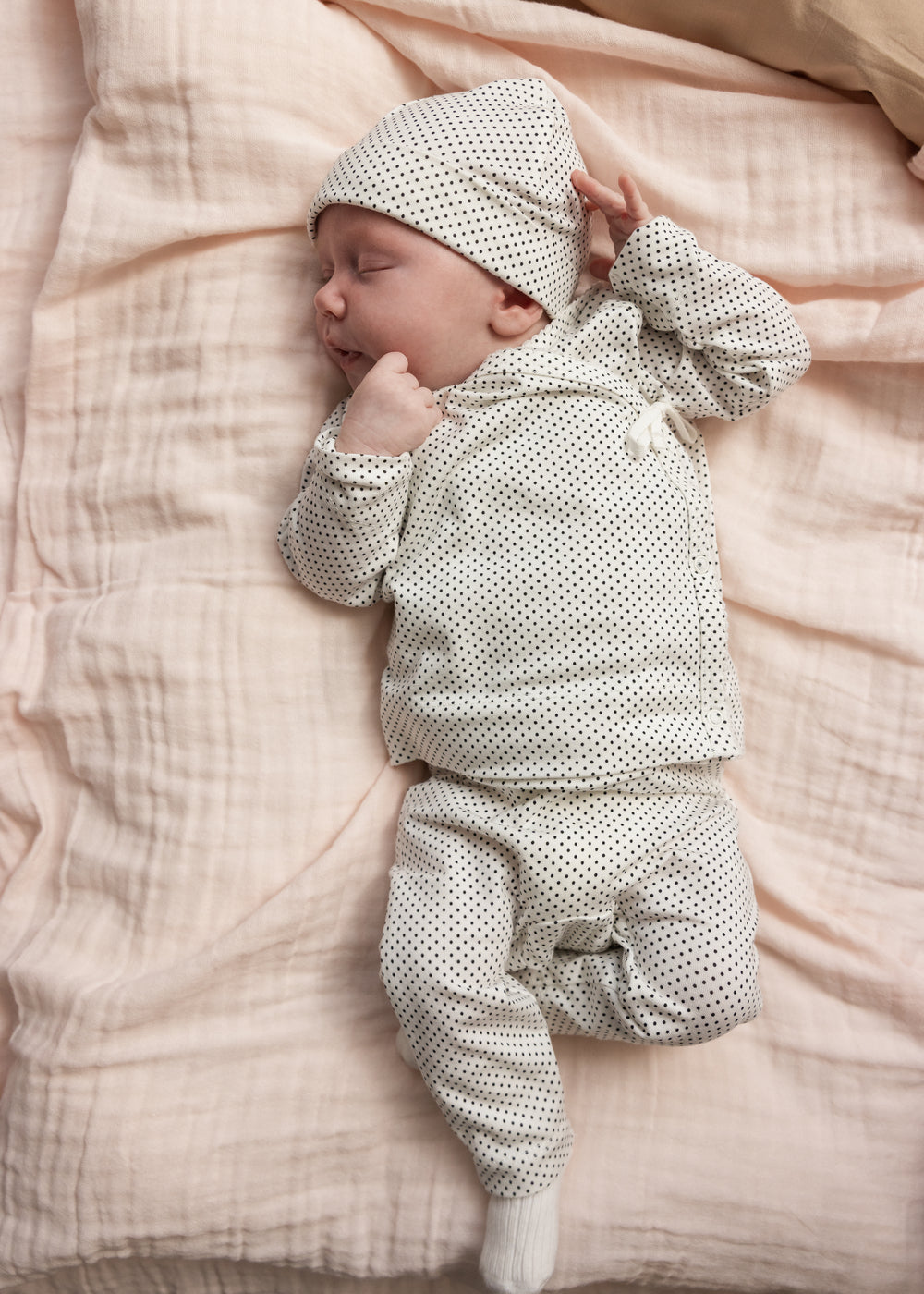 Prikket babyhue og heldragt i hvid med mørke prikker