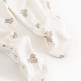 Hvid heldragt med beige teddybjørn-print og lange ben, set som close-up ved fødderne