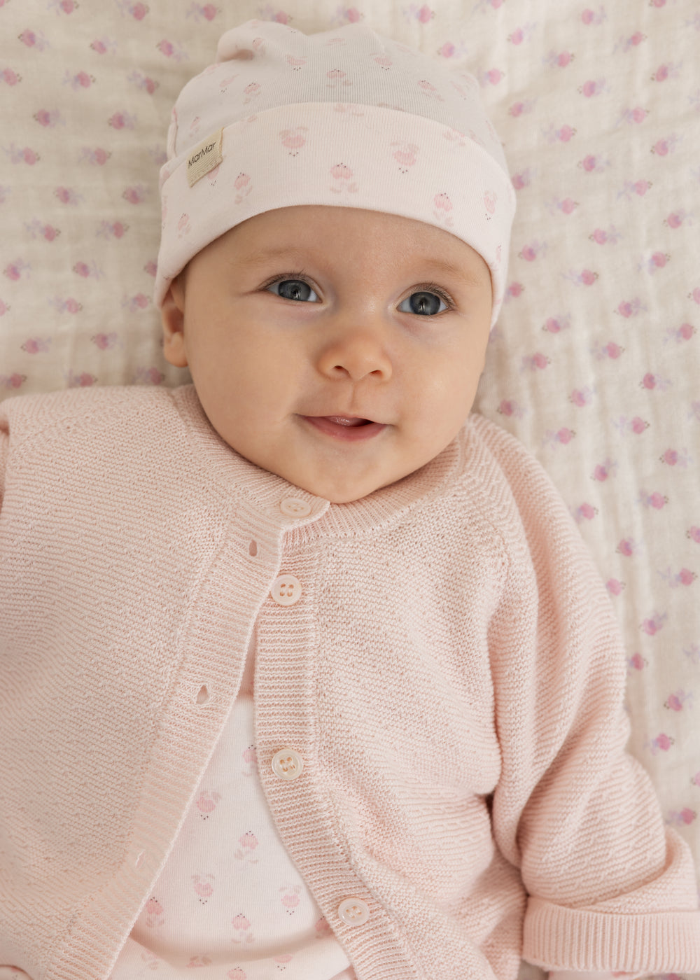Baby i lys heldragt med lyserøde striber og matchende hue