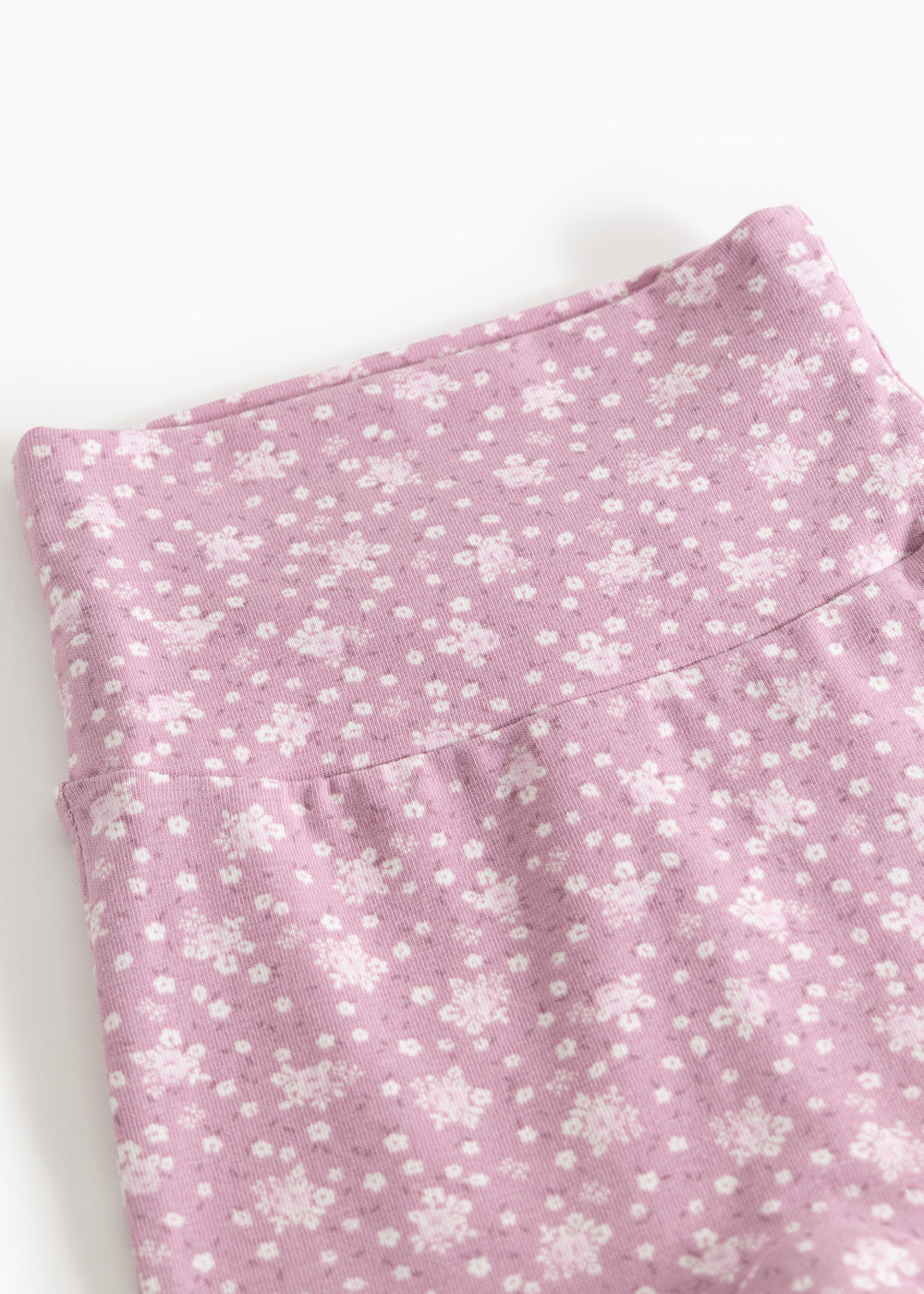 Lyserøde babybukser med små hvide blomsterprint og bred linning