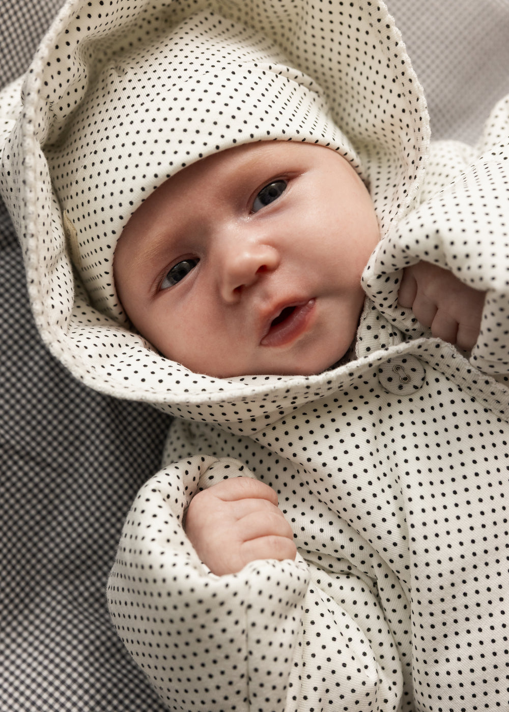Nyfødt baby i prikket babyhue med små mørke prikker