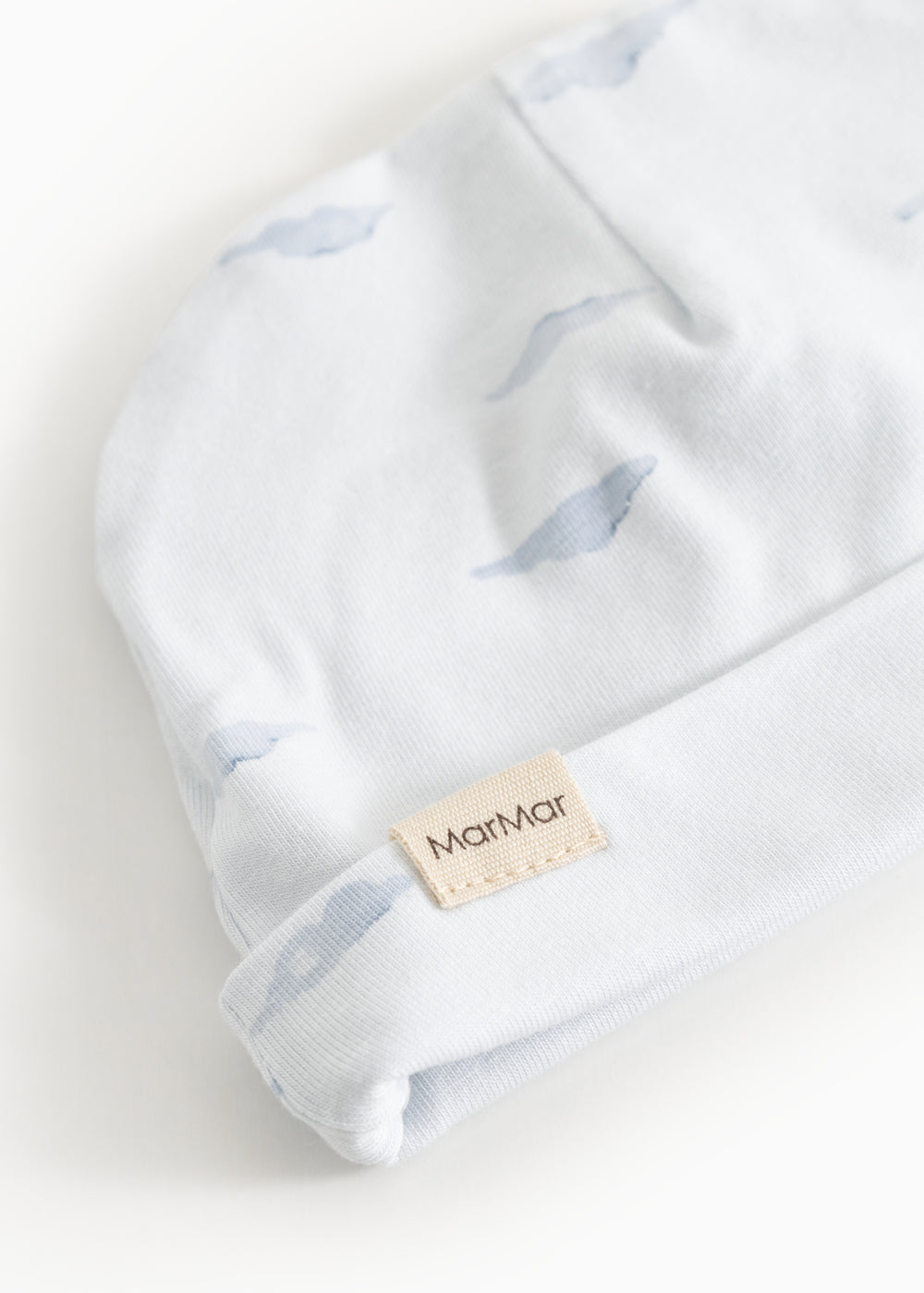 Aiko Cumu babyhue detalje: hvid kant med blåt hvalemønster og beige mærke