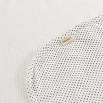 Tæppe med små sorte prikker og beige mærkeplade på hjørnet