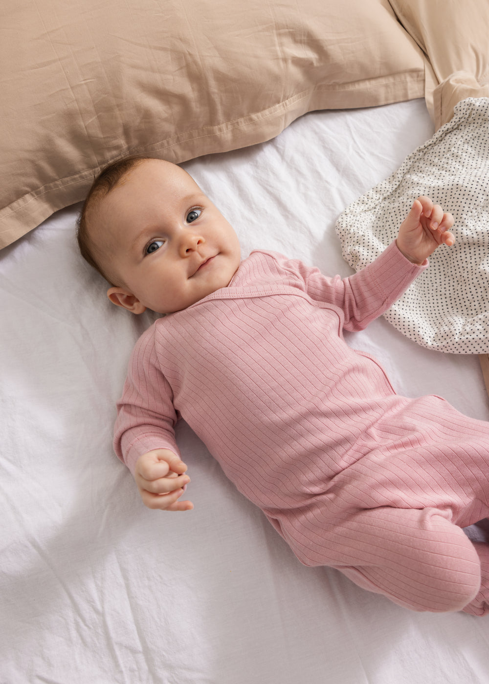 Stofblee med små sorte prikker under baby, lyserødt tøj synligt