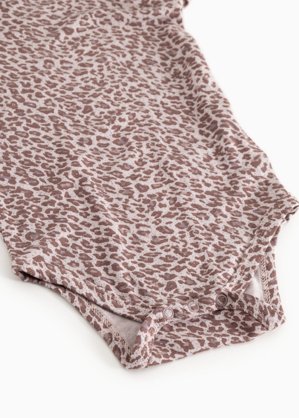 Close-up af bodydragt i støvet lilla med leopardmønster og elastisk kant ved ben