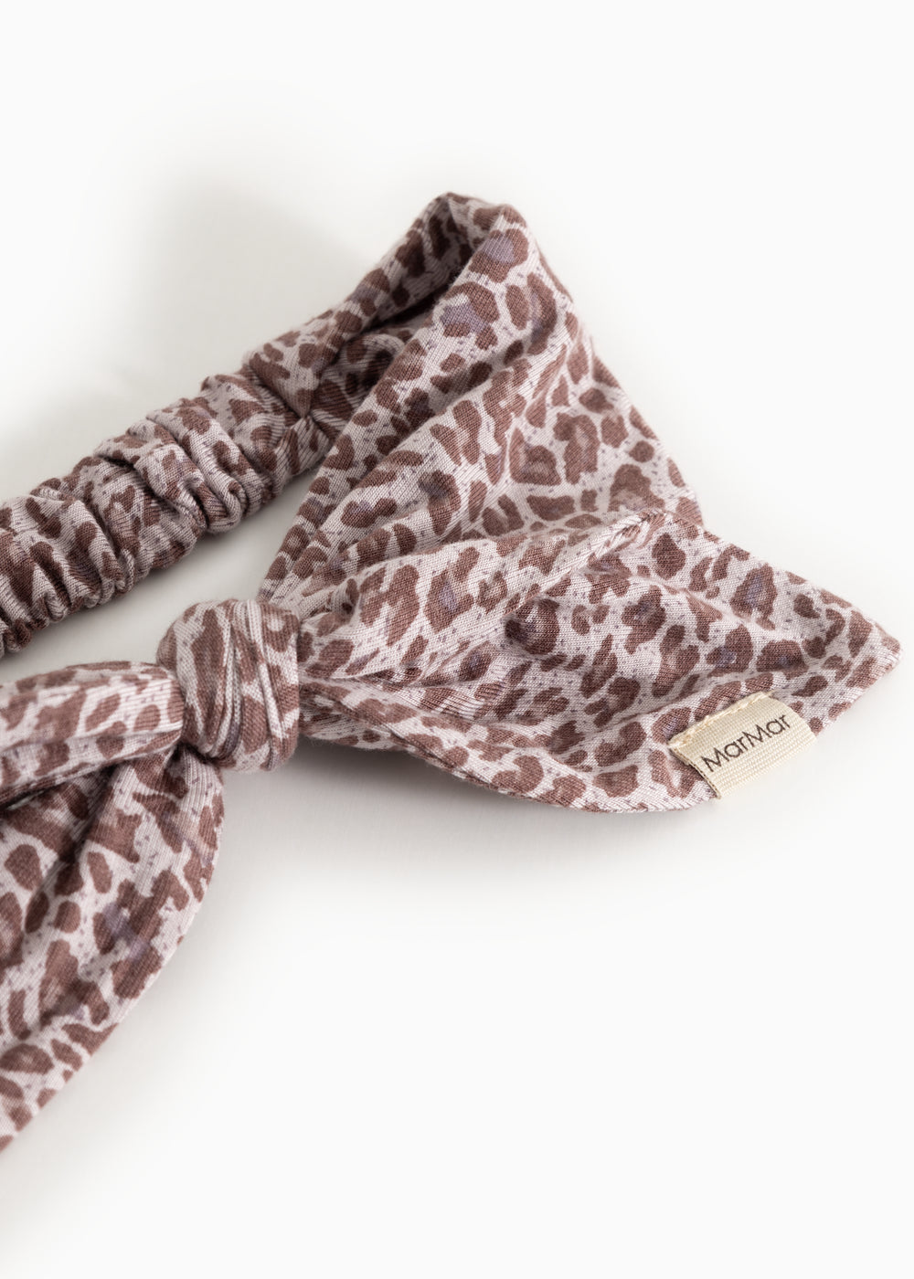 Hårbånd med leopardmønster i støvet lilla og rynket elastik, mærkat på siden.