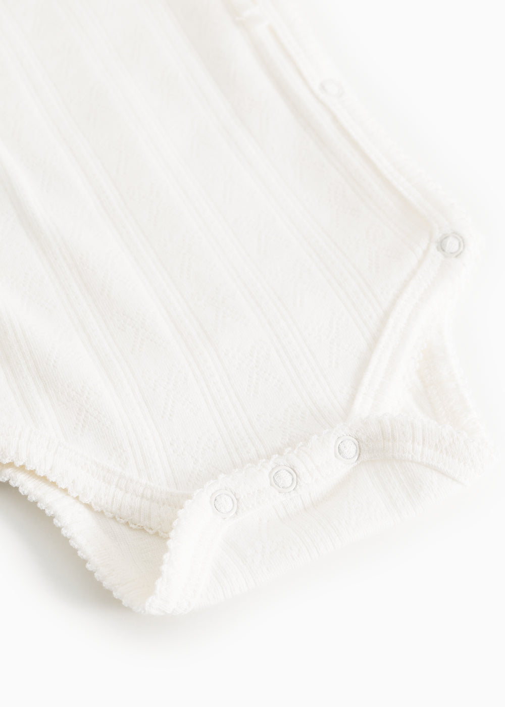 Hvid baby-bodystocking med trykknapper i skridtet og knaplukning ved halsen