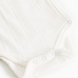 Hvid baby-bodystocking med trykknapper i skridtet og knaplukning ved halsen