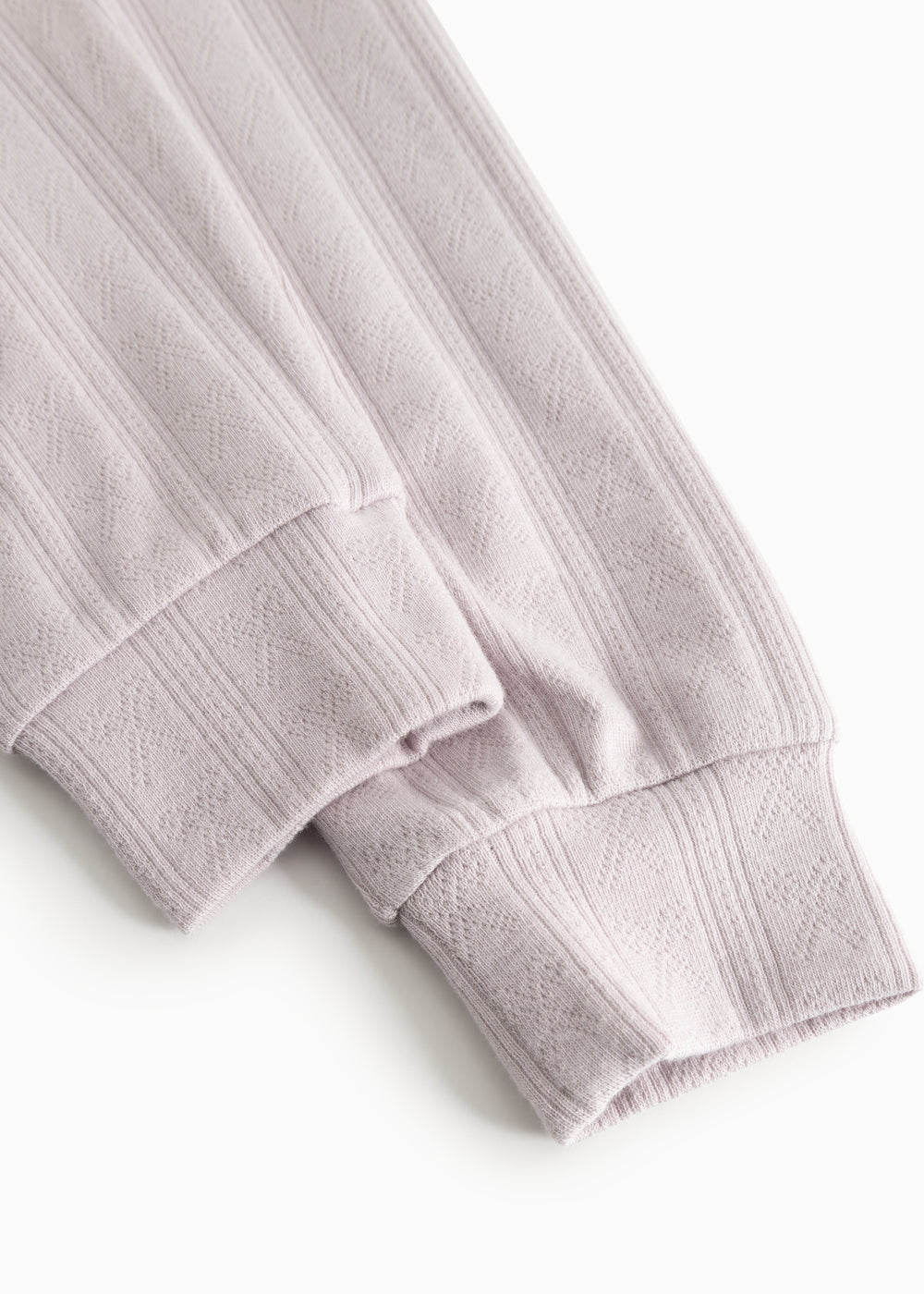 Børnepyjamas i lys lilla med ribkant og tekstureret stribemønster ved manchet.