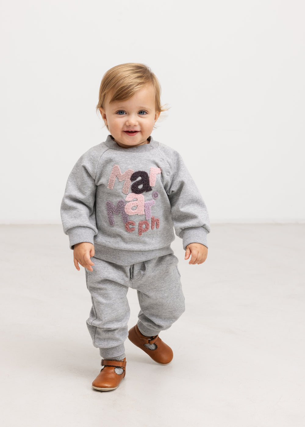 Grå babybluse med farvet bogstavprint, båret af lille barn
