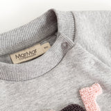 Grå babybluse med knapstolpe ved hals og farvet bogstavmotiv