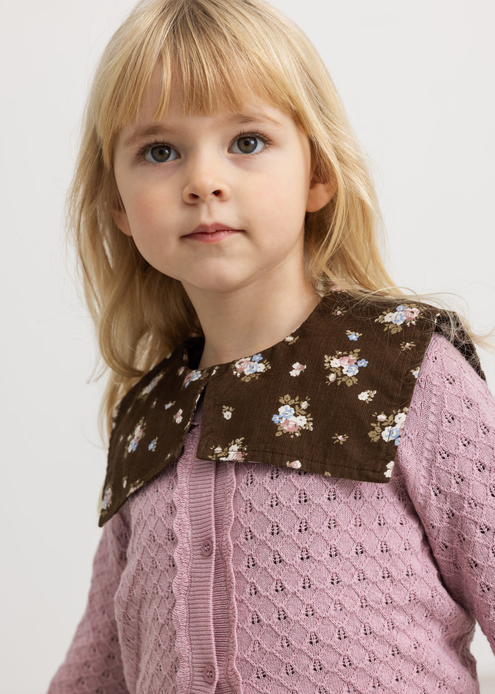 Barn iført strikket cardigan i soft berry med knaplukning og mønsterstrik