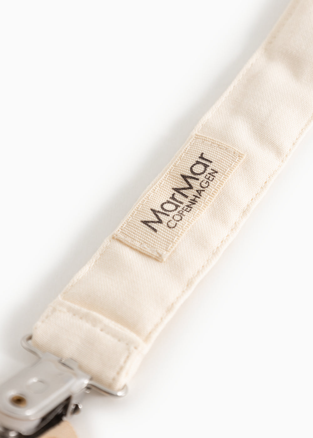 Nærbillede af Mamar Cotton-mærke på beige suttesnor i stof