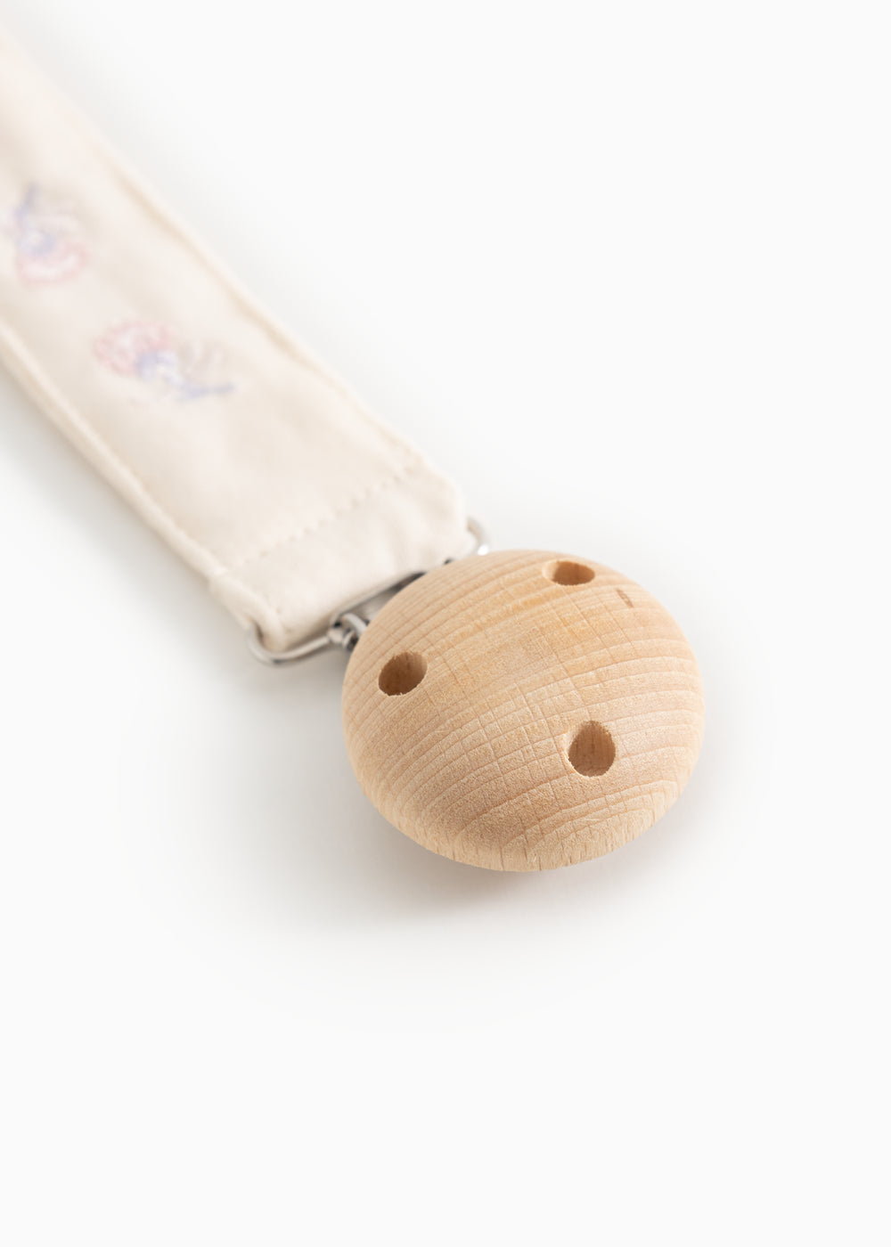 Beige suttesnor i stof med træclips og metalring samt blomsterbroderi