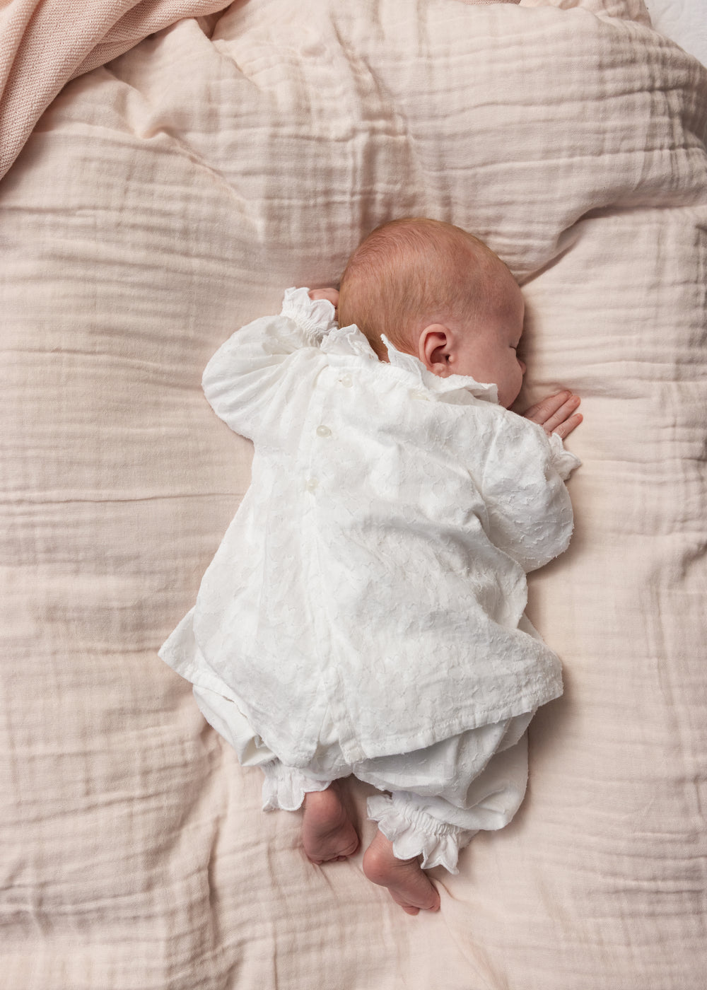 Hvide babybukser på baby, rynket look og flæsekant ved benafslutningen