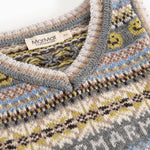 Strikvest med V-hals og Fair Isle-mønster, grå kant med gule detaljer.