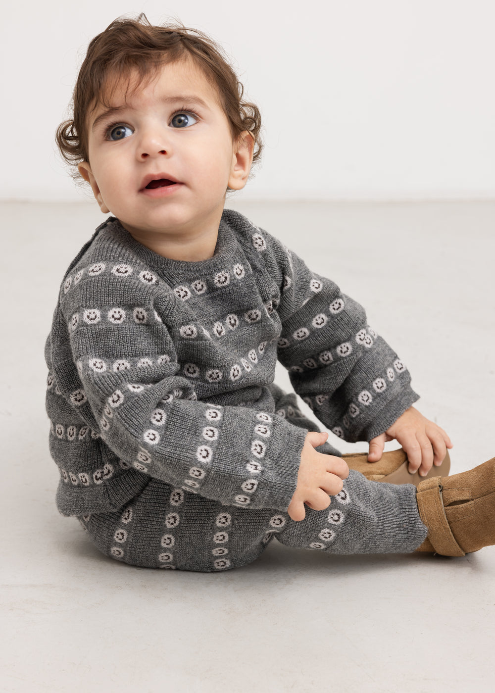 Grå strikbluse med knapper og allover mønster, set på baby
