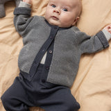 Strikket cardigan på baby med knaplukning, mørkeblå ribkanter og korte ærmer