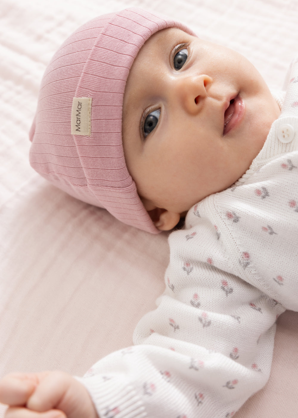 Lyserød babyhue på baby med hvid heldragt med små mønstre