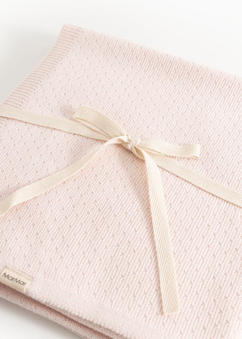Rosa strikket tæppe bundet med beige sløjfe i kanten