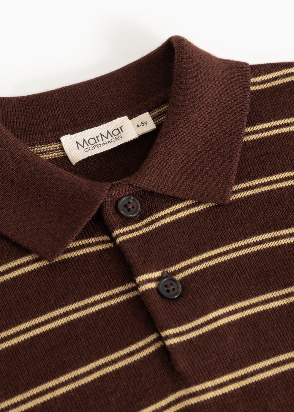 Detalje af strikpolo: ribkrave, knapper og beige striber på mørk bund