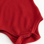 Kirsebærrød bodystocking med ribmønster og trykknapper ved skridtet.