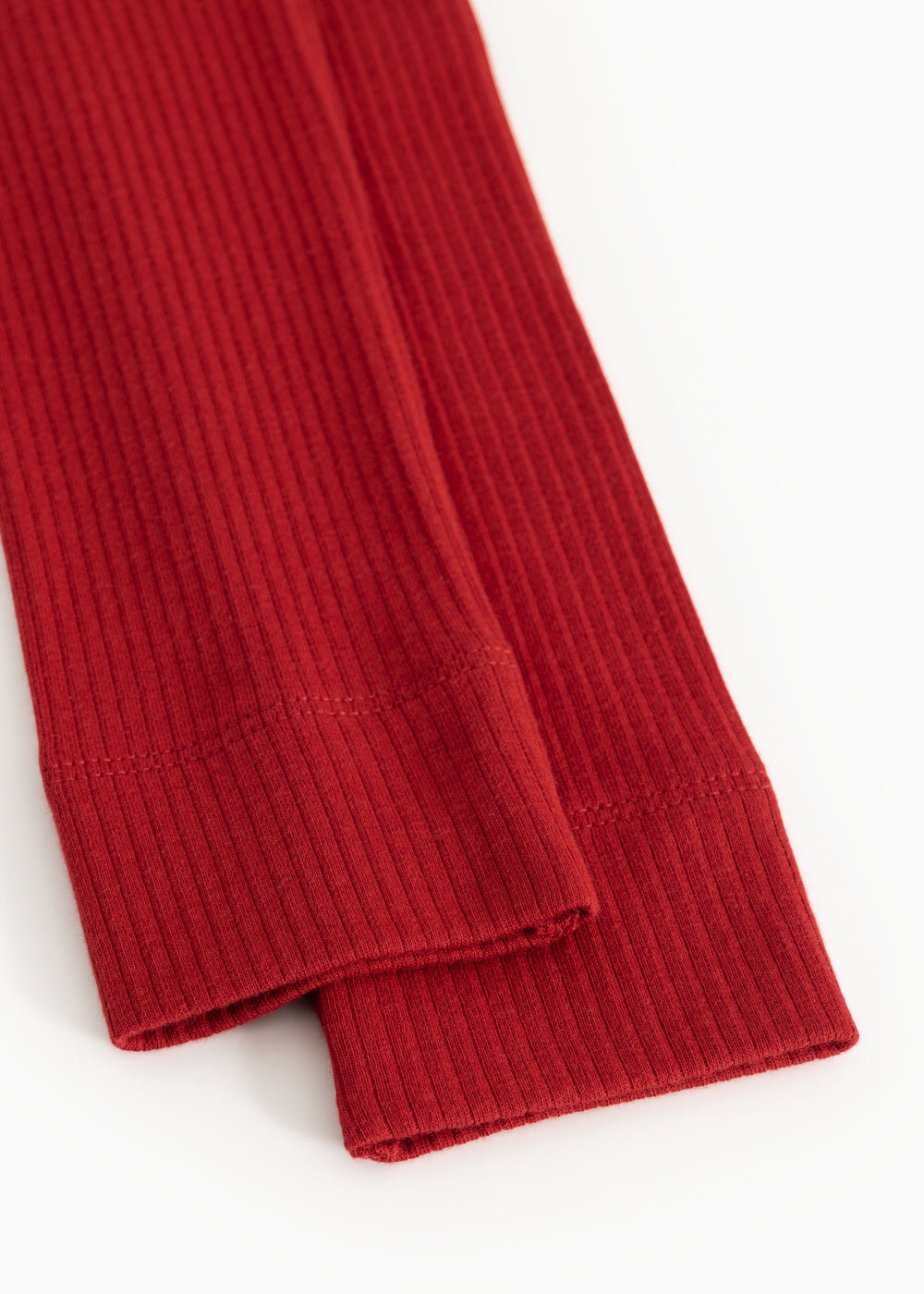 Detalje af røde ribstrikkede leggings med stram elastisk kant ved benafslutning