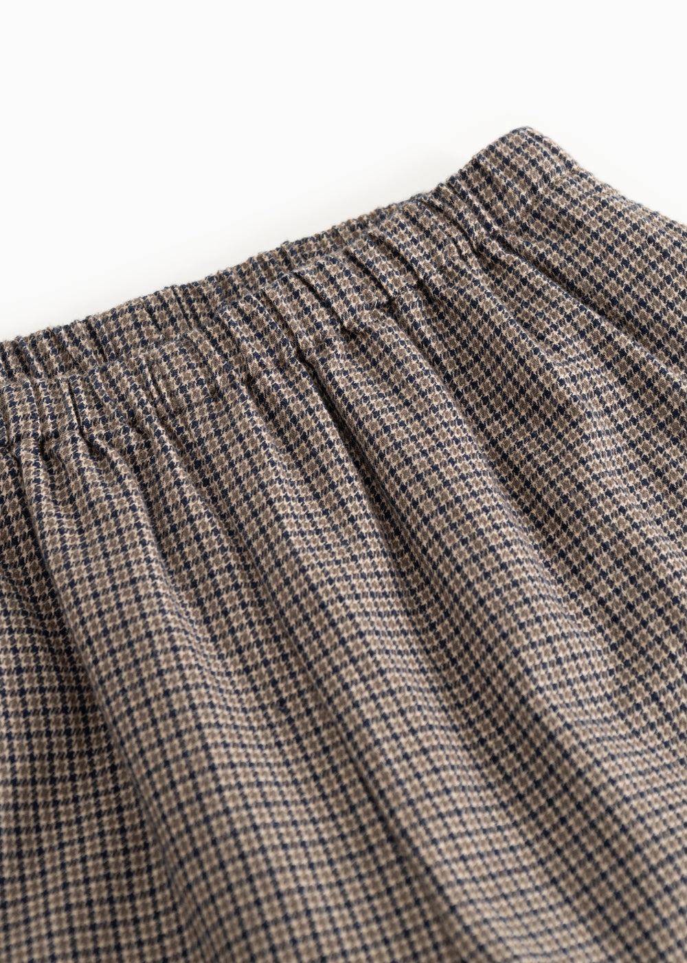 Detalje af houndstooth-bukser: elastisk linning og folder ved taljen.