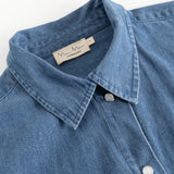 Detalje af blå denimskjorte: krave, knapper og inderside med mærketape