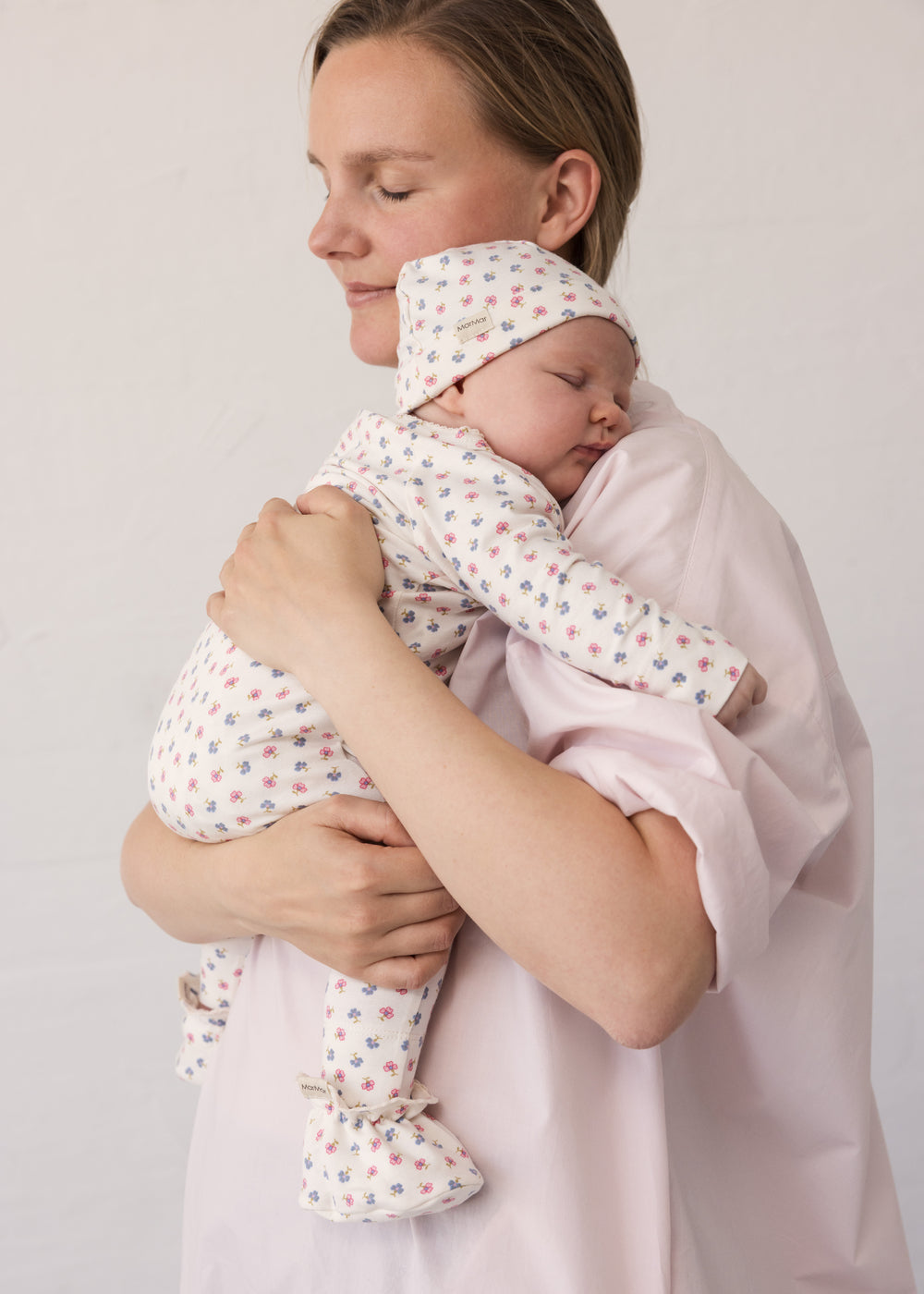 Kvinde iført lyserød kjole mens baby holdes i favn