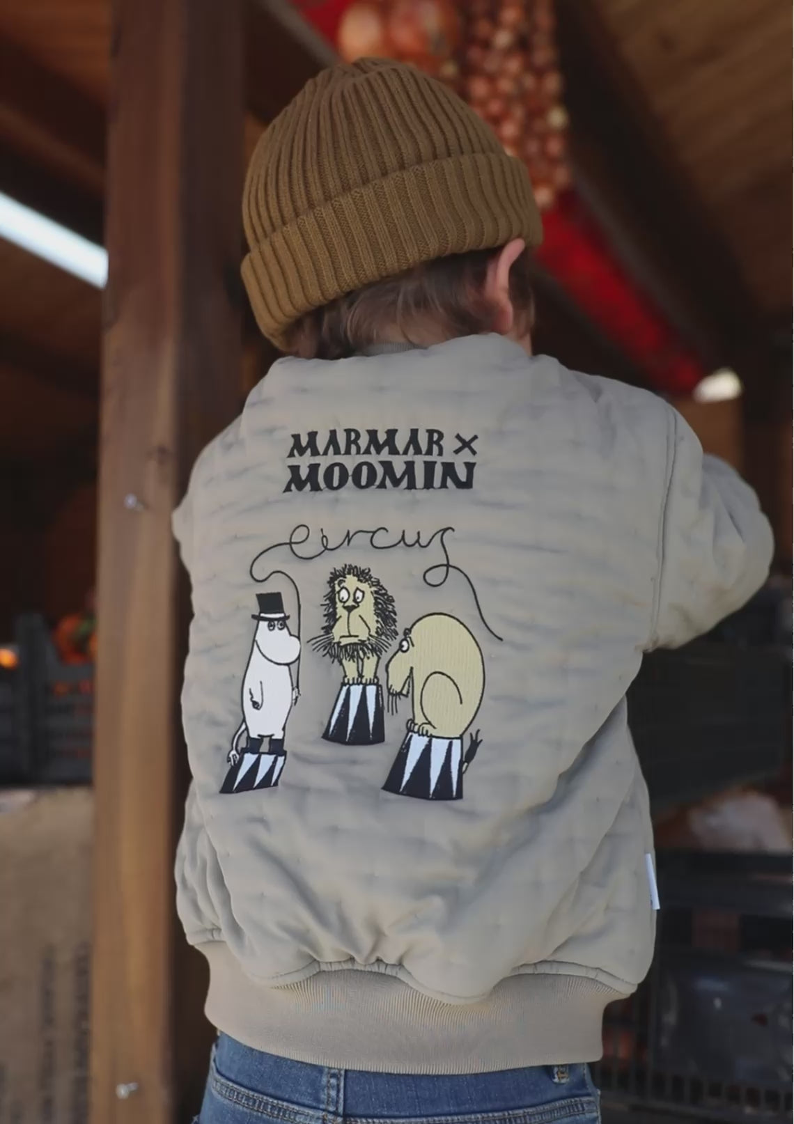 Barn set bagfra iført grøn jakke med Moomin print og brun hue
